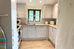 a kitchen with white cabinets and a sink at Towan Cottage - Cwc79064 in Perranporth +16 photos
