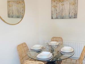 a glass table with two chairs and a mirror at Redcot Gardens in Stamford