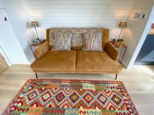 a brown couch in a living room with a rug at Oak Tree Retreat in Dronfield
