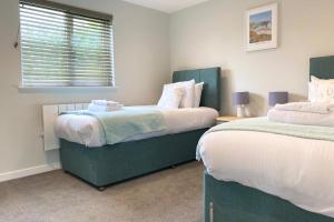 a bedroom with two beds and a window at Holywell - Cwc in Perranporth