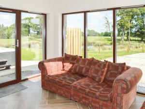 a brown couch in a living room with windows at The Farmhouse - Ukc6250 in Linlithgow