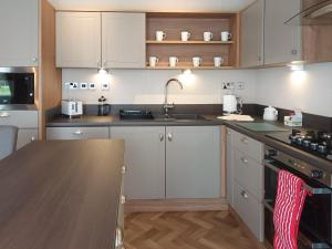 a kitchen with white cabinets and a wooden counter top at Rivendale 76 in St. Andrews +9 photos
