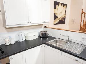 a kitchen with white cabinets and a sink at Appletree Cottage - Ukc6251 in Linlithgow