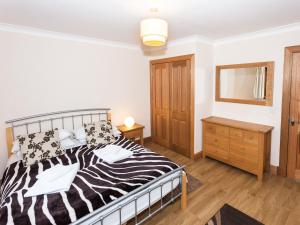 a bedroom with a black and white bed and a dresser at Appletree Cottage - Ukc6251 in Linlithgow