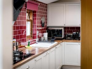 a kitchen with white cabinets and a red tile wall at The Servant's Hall - Ukc6964 in Carnoustie