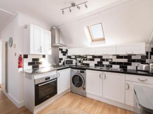 a white kitchen with black and white tiles on the wall at Fishermans's Rest in Lossiemouth