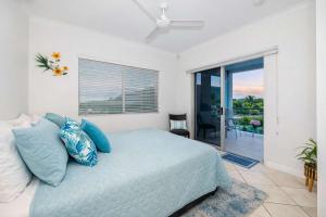 a bedroom with a bed with blue pillows and a balcony at 3BR Oceanfront Penthouse on The Strand, Townsville in North Ward