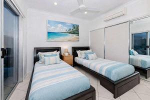 a bedroom with two beds in a room with a window at 3BR Oceanfront Penthouse on The Strand, Townsville in North Ward