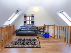 a living room with a black leather couch and a rug at Beech Cottage - Ukc6252 in Linlithgow