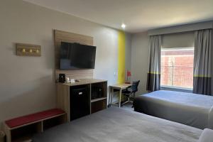 a hotel room with a bed and a flat screen tv at Super 8 by Wyndham Baytown in Baytown