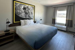 a bedroom with a large bed and a painting on the wall at Super 8 by Wyndham Baytown in Baytown