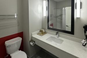 a bathroom with a toilet and a sink with a mirror at Super 8 by Wyndham Baytown in Baytown