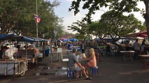 a group of people sitting at tables at an outdoor market at KODO Guest House in Nathon Bay