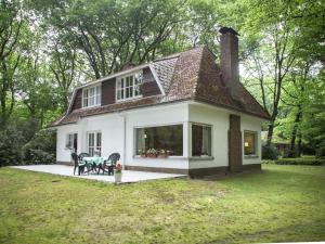 uma pequena casa branca com uma mesa no quintal em This atmospheric holiday home em Zoersel