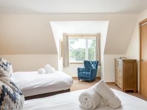 a bedroom with two beds and a blue chair at Emsdorf Lodge - Ukc5800 in Lundin Links