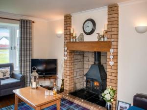 a living room with a brick fireplace with a clock at The Cairngorm - Ukc5051 in Aviemore