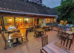 a deck with tables and chairs and a restaurant at Malkoha Lake St Lucia in Hluhluwe