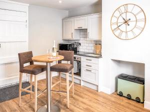 a kitchen with a table and chairs and a clock at Symond House-Ukc5530 in Bury Saint Edmunds