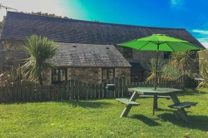 a picnic table with a green umbrella in a yard at Fistral Cottage - Cwc46839 in Perranporth