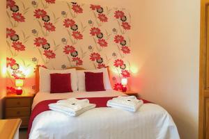 a bedroom with a bed with red flowers on the wall at Fistral Cottage - Cwc46839 in Perranporth