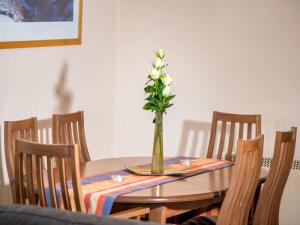 a dining room table with a vase with flowers in it at Munro View - Ukc5040 in Aviemore