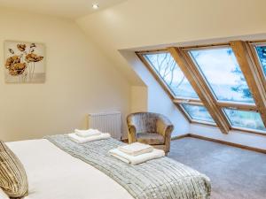 a bedroom with a bed and a chair and a window at Homelands-Keil in Lundin Links