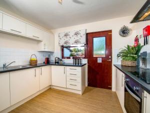 a kitchen with white cabinets and a red door at The Stag-Ukc5066 in Aviemore