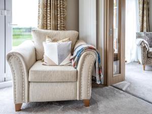 a chair with pillows on it in a living room at Rivendale in St. Andrews