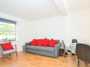 a living room with a gray couch with red pillows at Pebble Cottage in Ventnor
