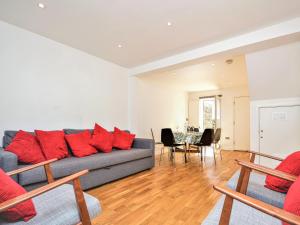 a living room with a gray couch and red pillows at Pebble Cottage in Ventnor