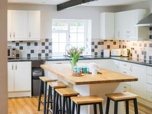 a kitchen with white cabinets and a wooden island with stools at Number Six - Ukc4968 in Tawstock