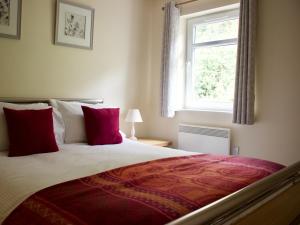 a bedroom with a bed with red pillows and a window at Pine View in Invergarry