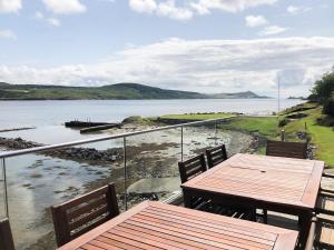 a balcony with two tables and a view of the water at Dunmore Villa-Uk36498 in Tarbert +1 photo
