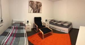 1 Schlafzimmer mit 2 Betten, einem Stuhl und einem orangenen Teppich in der Unterkunft Apartment Kreuzstraße in Hürth