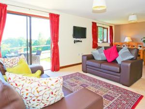 a living room with a couch and a tv at Holly Cottage in Uckfield