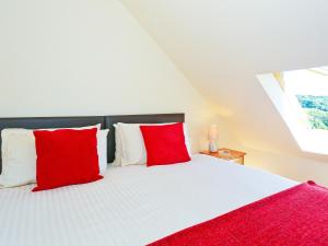 a bedroom with a bed with red and white pillows at Holly Cottage in Uckfield