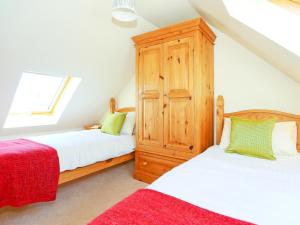 a attic bedroom with two beds and a wooden cabinet at Holly Cottage in Uckfield