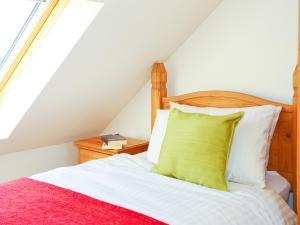 a bedroom with a bed with a yellow pillow at Holly Cottage in Uckfield +3 photos