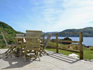 a wooden table and two chairs sitting on a patio overlooking the water at Tigh Beg in Lerags