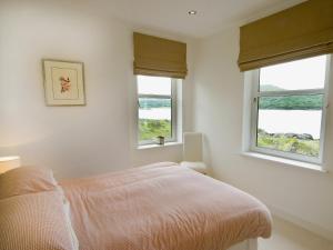 a white bedroom with two windows and a bed at Tigh Beg in Lerags