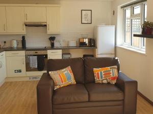 a living room with a brown couch in a kitchen at Elm Cottage in Uckfield