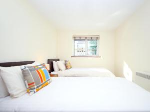 a white bedroom with two beds and a window at Elm Cottage in Uckfield