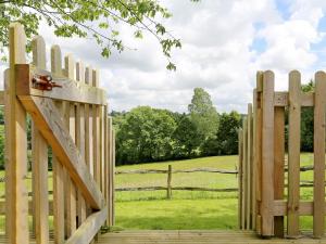 a wooden gate with a field behind it at Elm Cottage in Uckfield