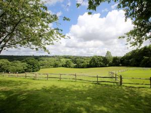 a wooden fence in a grassy field with trees at Elm Cottage in Uckfield +7 photos