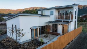 a white house with a fence and mountains in the background at 月詠 Tsukuyomi in Fujikawaguchiko