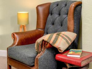 a chair with a pillow and a book on a table at The Lodge in Duffus