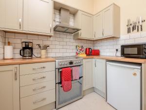 a kitchen with white cabinets and a stove top oven at The Lodge in Duffus