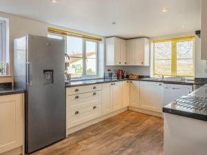 a kitchen with a stainless steel refrigerator and white cabinets at Nutley Farmhouse in Uckfield