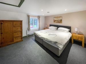 a bedroom with a bed and a dresser and a window at Nutley Farmhouse in Uckfield
