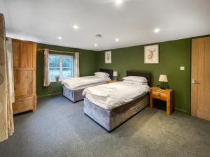 two beds in a room with green walls at Nutley Farmhouse in Uckfield